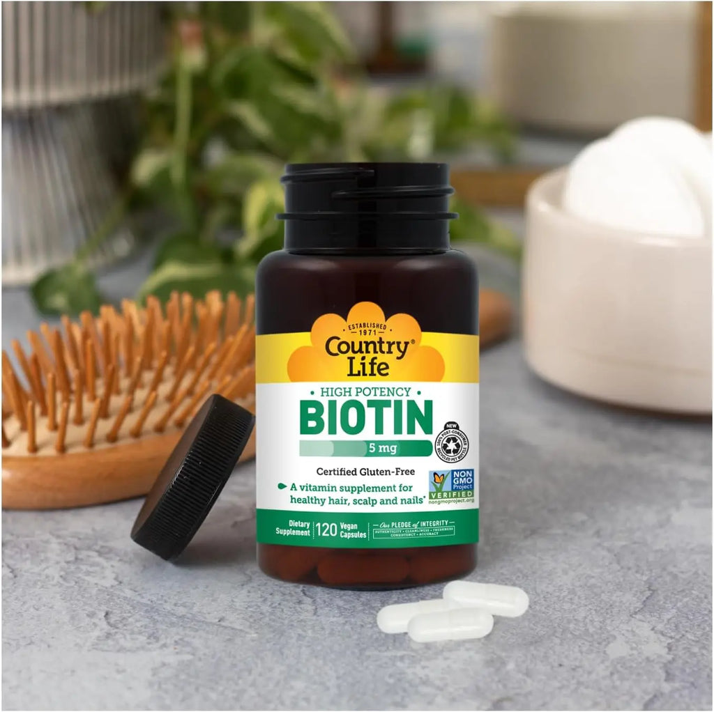 Country Life Biotin 5mg bottle with cap off and pills on gray surface with wooden brush