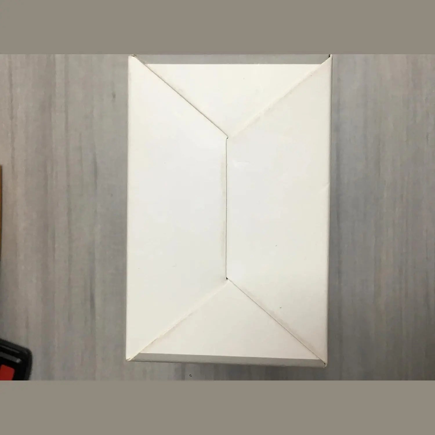 Folded white shipping box for black action camera with red accessory detail
