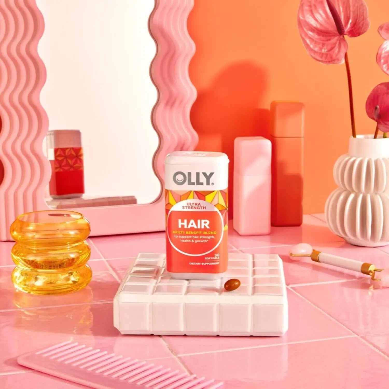 OLLY Ultra Strength Hair Softgels bottle with strawberry flavor softgel on pink tiled floor