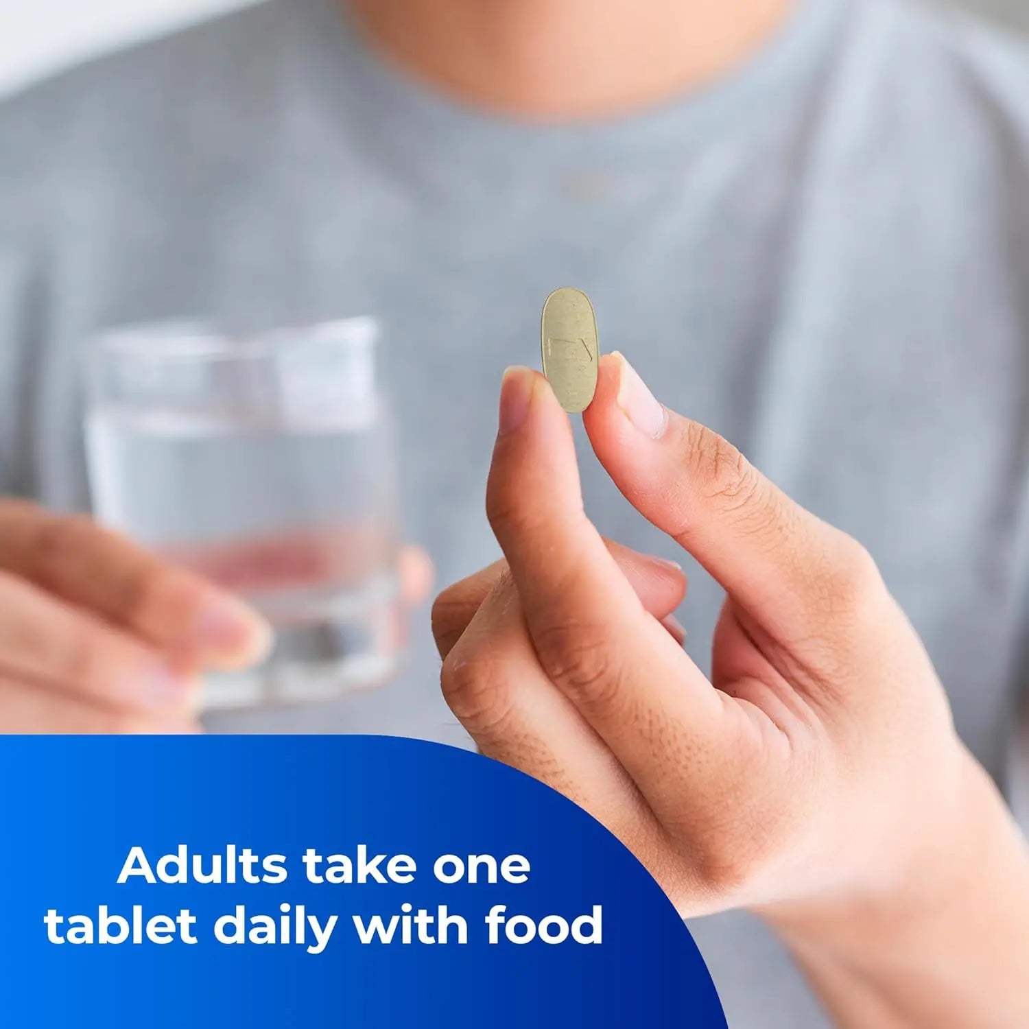 Man holding yellow One A Day pre-conception health tablet with water